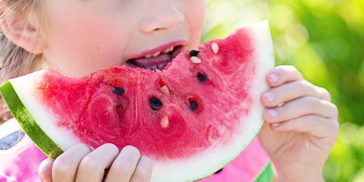 Niña comiendo una porción de sandía.