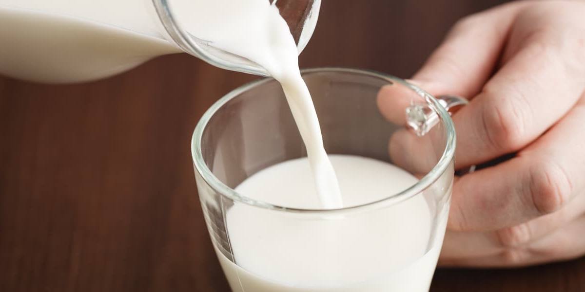 vaso-leche Joven sirviendo un vaso de leche.