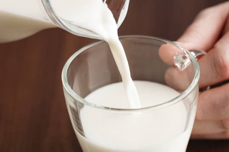 Joven sirviendo un vaso de leche.