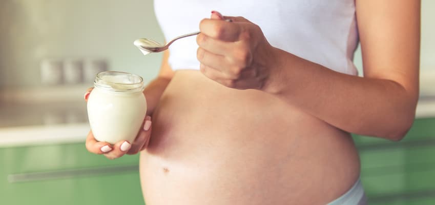 Joven embarazada comiendo un yogur natural.