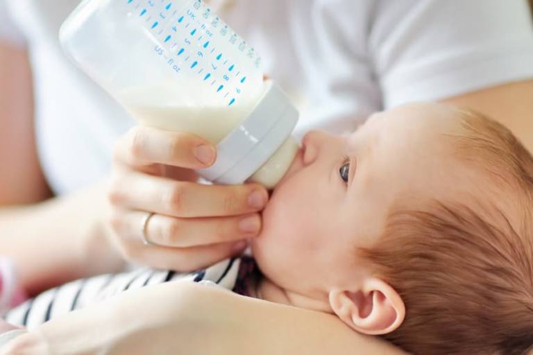 Una madre dando el biberón a su hijo.