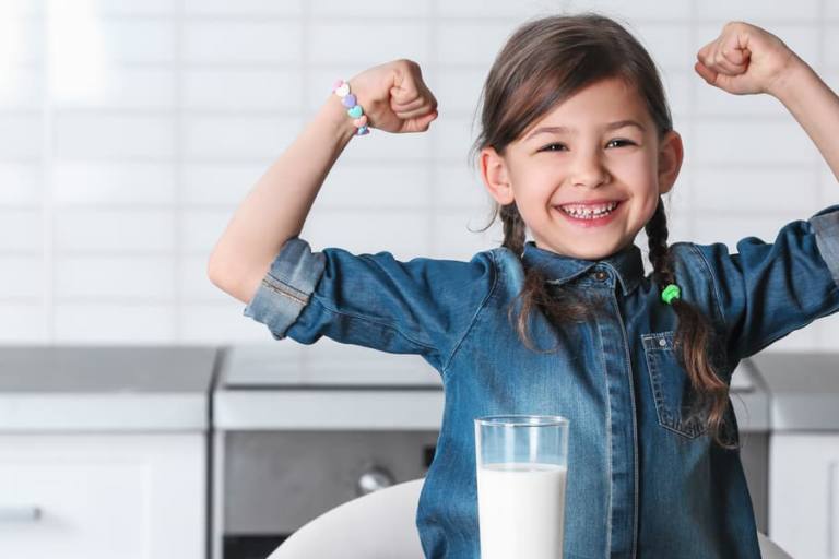 Niña con un vaso de leche.
