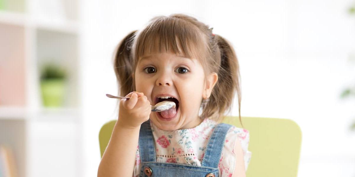 Niña comiendo un yogur.