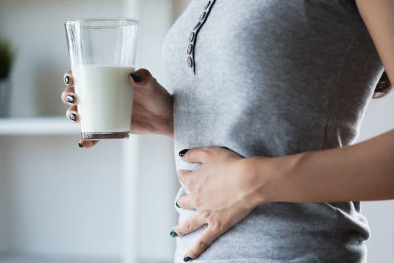 mujer con intolerancia a la lactosa con dolor después de tomar leche