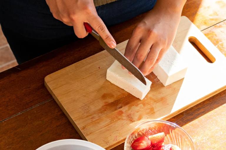 Mujer cortando queso.