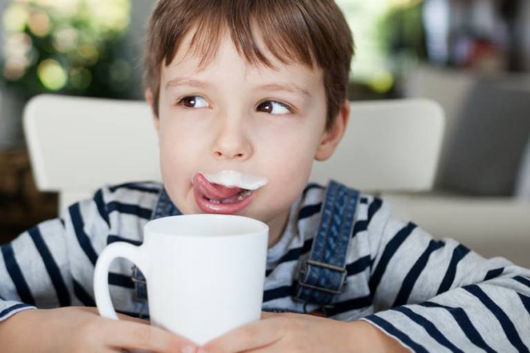 Niño bebiendo un vaso de leche.