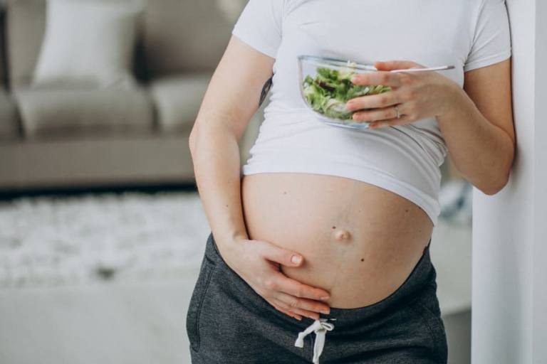 Mujer embarazada comiendo una ensalada.