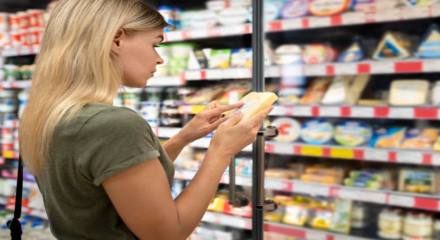 mujer comprobando la fecha de caducidad de un producto lácteo en el supermercado