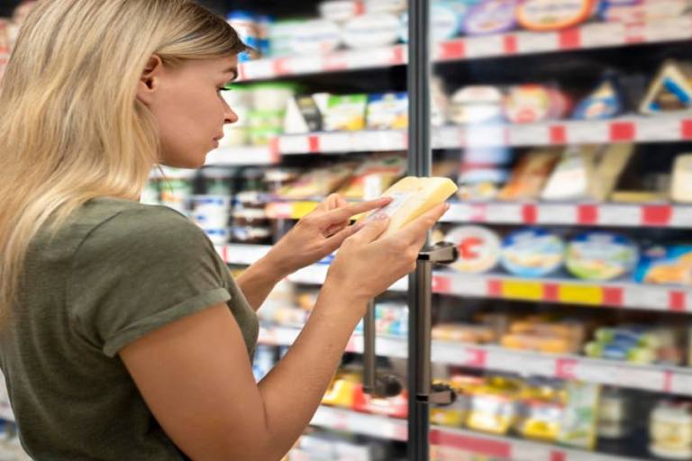 mujer comprobando la fecha de caducidad de un producto lácteo en el supermercado